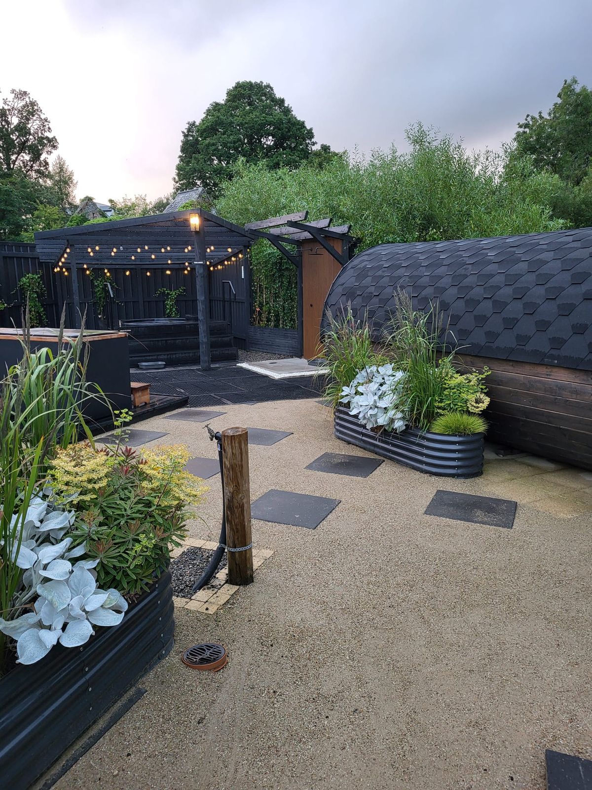 Stepping stones through the courtyard towards the barrel sauna and the string-lit pergola