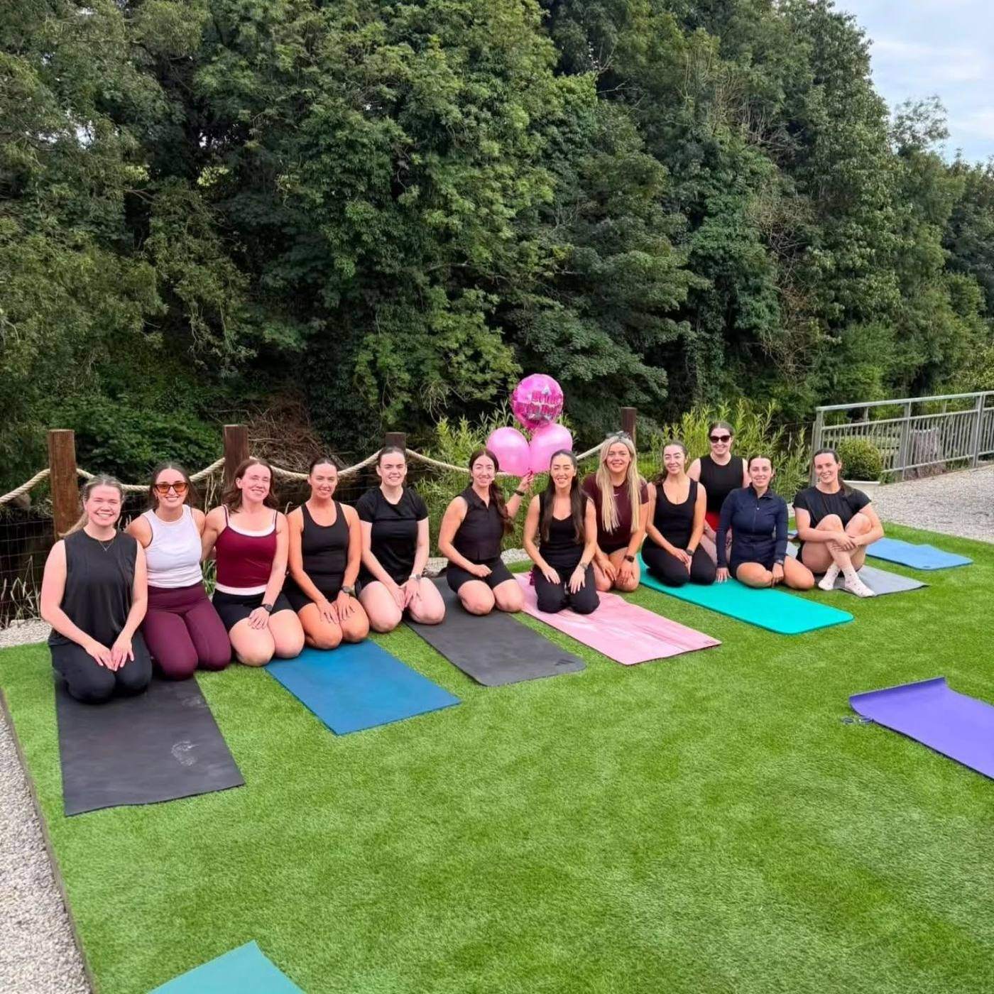 A group on yoga mats on the lawn beside the river