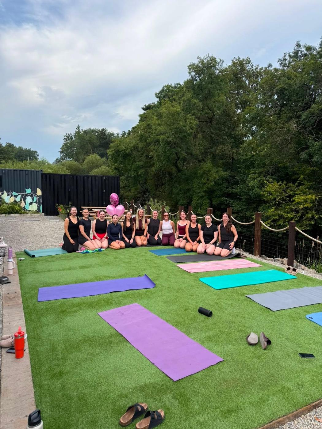 A hen party on yoga mats by the river, with pink balloons