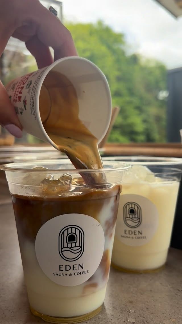 Espresso being poured over an iced latte in an Eden cup
