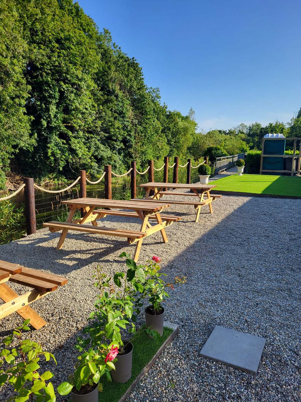 Picnic tables along the riverbank in the sun